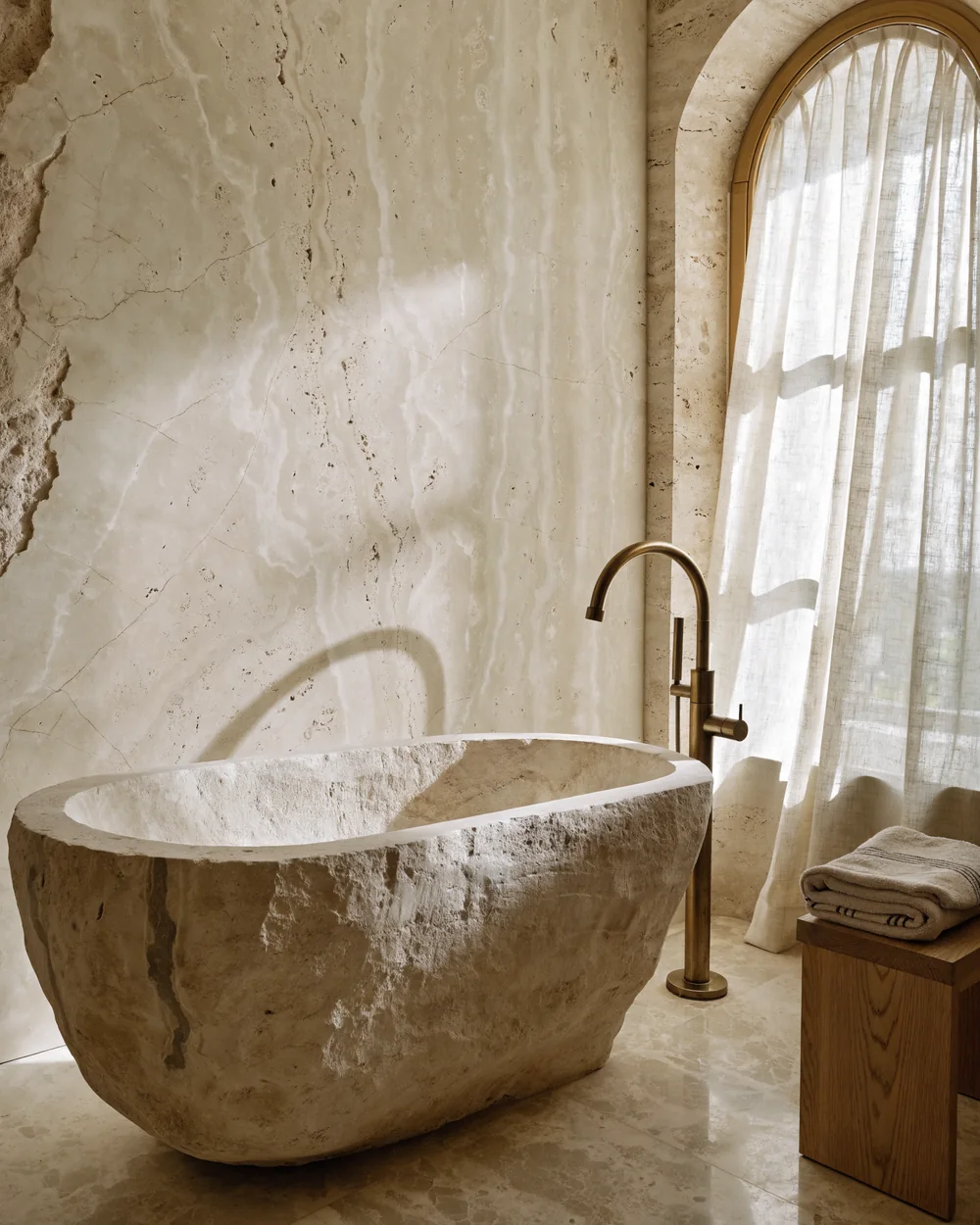 Primary bathroom with stone soaking tub and travertine wall